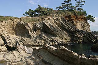 対岸から見た立入禁止区域の岩場とその上の丘